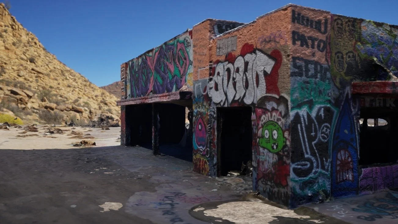 3D render of the photogrammetry-scanned graffiti building placed in a desert scene with a rocky hillside behind