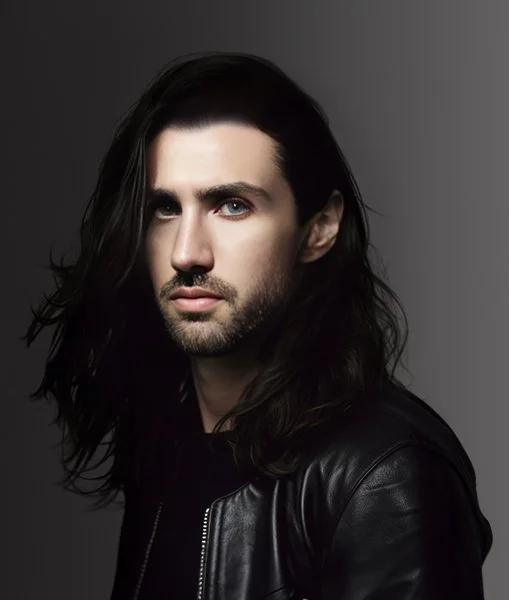 Stephen Wilcox, founder and director of Final Form Studios, with long dark hair and a black leather jacket on a grey backdrop