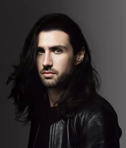 Stephen Wilcox, founder and director of Final Form Studios, with long dark hair and a black leather jacket on a grey backdrop